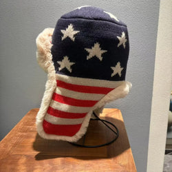 American flag patterned hat with fur trim on a wooden surface