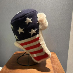 Knitted stocking with American flag design on a wooden stand against a gray wall.