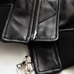 Close-up of a black leather jacket with zippers on a light background