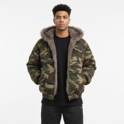 Man wearing a camouflage jacket with fur-lined hood on a white background