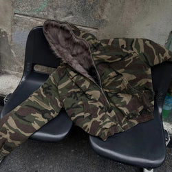 Camouflage jacket with fur lining draped over a black chair against a concrete wall.