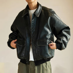 Person wearing a black leather jacket with a neutral background