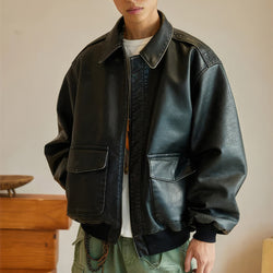 Person wearing a black leather jacket indoors with a neutral background