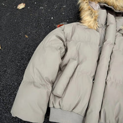 Gray puffer coat with fur-lined hood on a dark surface