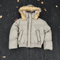 Gray puffer jacket with fur-lined hood on a dark surface