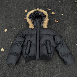 Black puffer jacket with fur-lined hood on a dark textured surface.