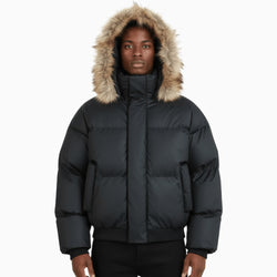 Person wearing a black puffer jacket with a fur-lined hood on a white background