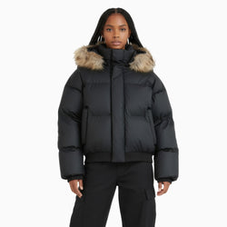 Person wearing a black puffer jacket with fur hood on a white background